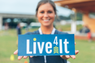 young woman holding a live4it sign at a live4it event